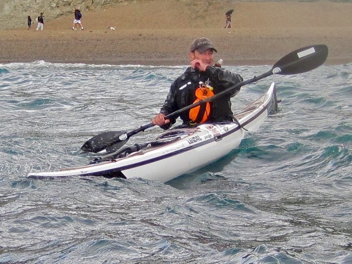 Launching sea kayak in bumpy sea conditions in Dorset, UK with NOMAD Sea Kayaking.